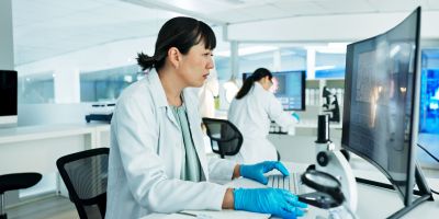 Scientist, woman and reading by computer in lab with medical research, review or solution with phar.